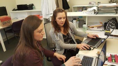 Two women sitting at desk working on laptops