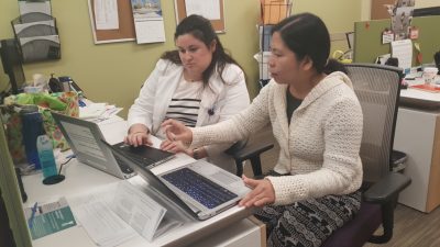 Two women sitting at desk working on laptops